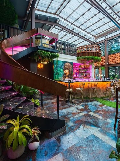 The sculptural spiral staircase at 'Highdrate' is a key feature, connecting the levels with a flourish. Surrounded by lush plants and colorful lighting, it's a perfect example of functional art.