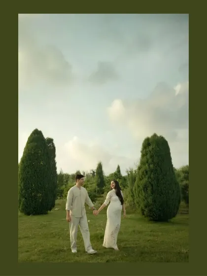 A walk to remember. This wide shot captures the couple in a beautiful, open landscape, holding hands as they begin their journey into parenthood. The composition emphasizes the start of a new adventure together.