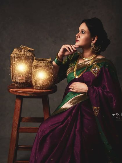 A thoughtful, seated pose. The warm light from the lanterns creates a cozy and intimate atmosphere for this traditional portrait.