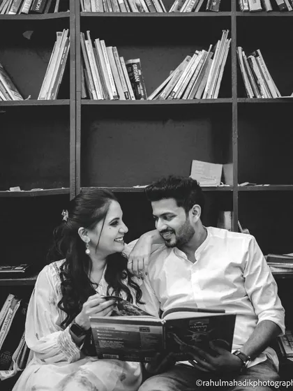 A black and white shot of the couple sharing a book in a library setting. This themed photo is a wonderful way to incorporate a shared hobby into a pre-wedding shoot, making it personal and unique.