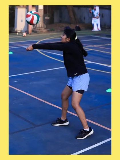 A female player executes a perfect underarm pass, her arms forming a solid platform to direct the ball. This is fundamental technique in action.