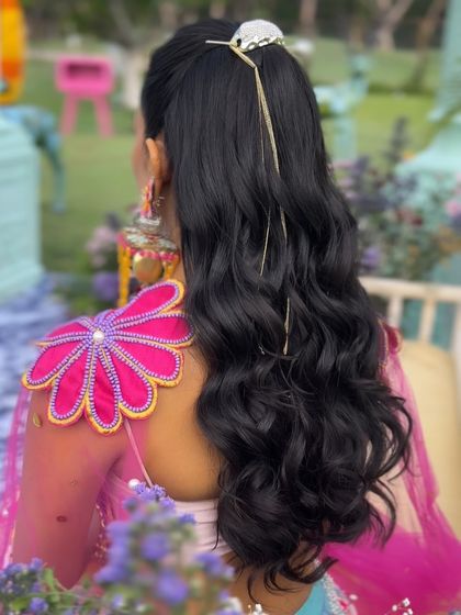A back view of the wavy high ponytail, adorned with a simple, modern hair accessory.