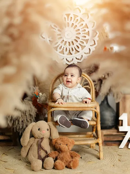 A happy baby boy surrounded by his furry friends during his half birthday shoot. The warm, neutral tones of the boho setup create a calming and beautiful scene.