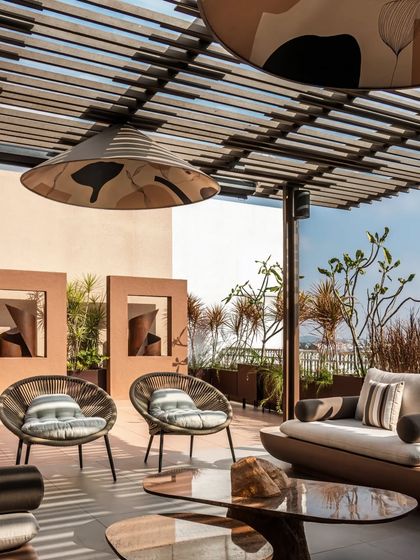 A view highlighting the relationship between the seating area and the corten steel art installations. The design integrates art and furniture to create a cohesive and sophisticated outdoor gallery.