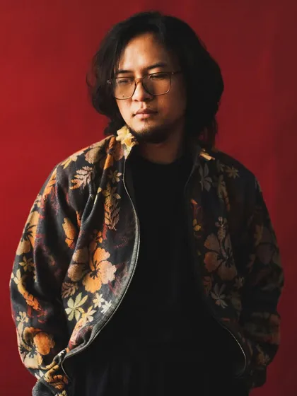 Taba Chake against a bold red background. The color adds a layer of intensity and passion to this portrait of a musician.