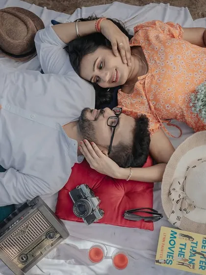 An overhead view of a cozy, retro-themed picnic. I focus on capturing these candid, joyful interactions and the little details that make your relationship special, from the vintage radio to the shared laughter.