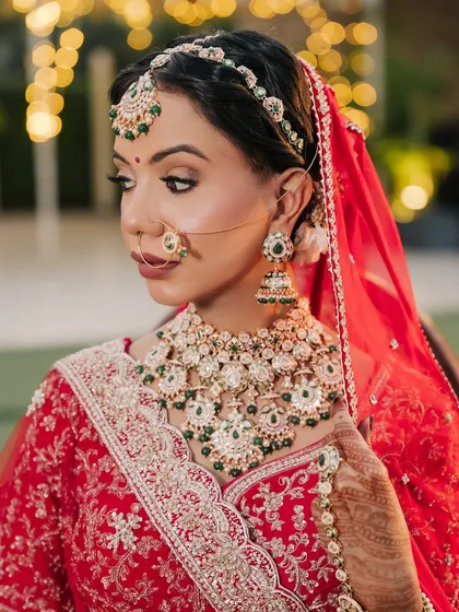 A close-up of this classic red bridal look. I focused on creating flawless, glowing skin and defining the eyes to complement her beautiful green and kundan jewellery. This is timeless elegance.