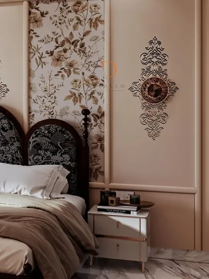 A close-up of a neo-classical bedroom, highlighting the elegant wall mouldings, floral wallpaper inserts, and a beautifully curved upholstered headboard.