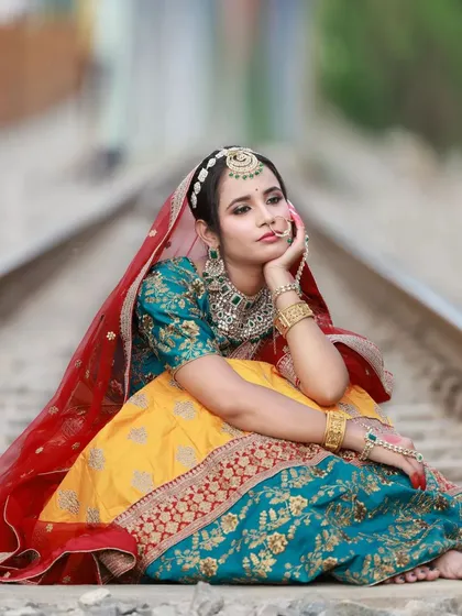 A quiet, thoughtful pose on the railway tracks. This composition focuses on the model's expression and the beautiful drape of the multi-colored lehenga, telling a story with the scene.