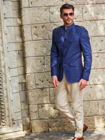 A confident pose against a stone wall highlights the texture and rich color of the blue linen jacket, proving that comfort and high style can coexist.