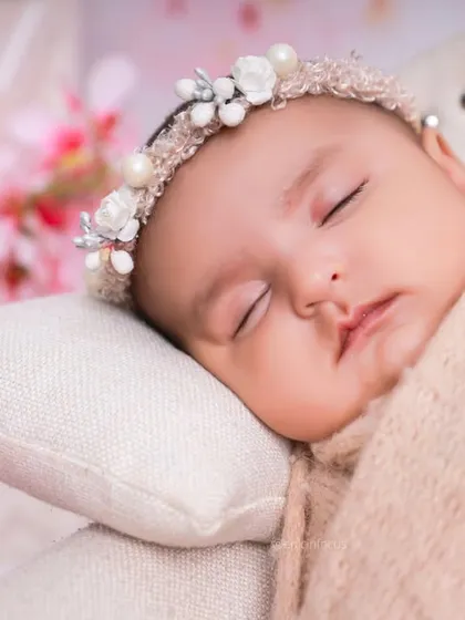 A close-up of the baby's face from the cherry blossom session, wearing a beautiful pearl and flower crown.