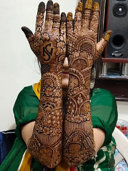 I love this pose because it shows off the complete bridal henna from palms to elbows. This design features the initials 'NS' for the couple, hidden within a dense pattern of traditional motifs.