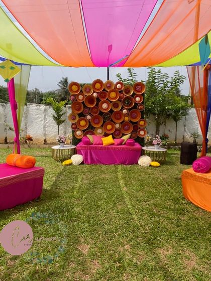The seating area for a Mehendi, featuring a unique backdrop made of woven baskets and colorful cushions.