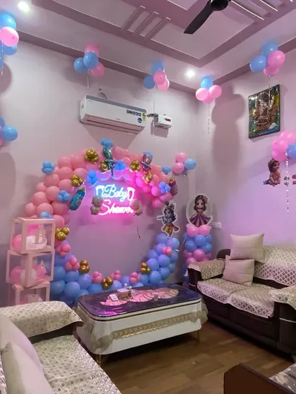A cozy living room transformed for a Kanha ji themed baby shower. The circular balloon arch and neon sign make a beautiful focal point, even in a smaller space.