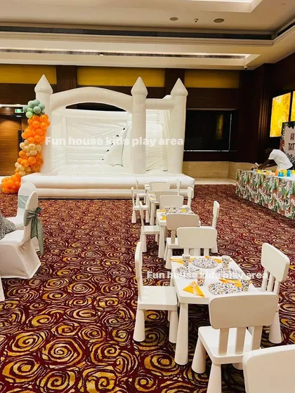 A wider angle of our large white bouncy castle and kids' dining area in a hotel ballroom. This demonstrates how we can create a complete party zone even in a formal indoor setting.