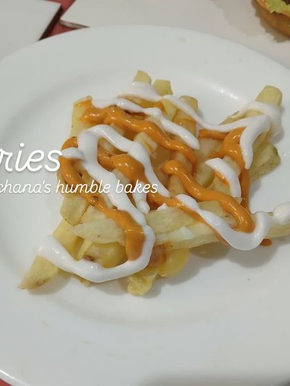 A simple plate of crispy french fries drizzled with mayonnaise and a tangy orange sauce. A classic snack that everyone loves, perfect as a side or on its own.