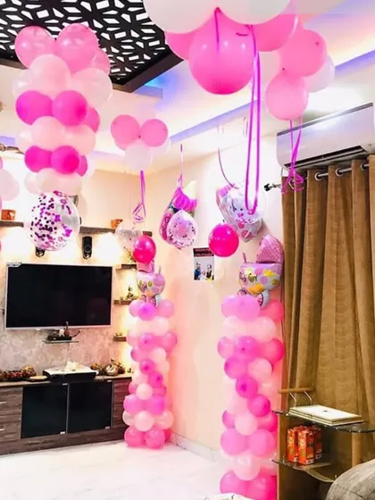 Another angle of the pink and white welcome home decoration, showing how the balloon pillars and ceiling decor fill the entire living space to create a celebratory atmosphere.