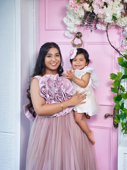 A close-up of a happy mother and her baby. The large floral detail on the Bloom gown adds a beautiful, textural element to the photo.