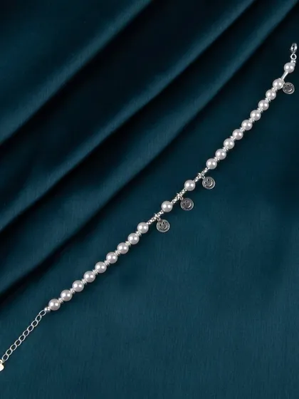 A pearl bracelet with small, circular silver charms.