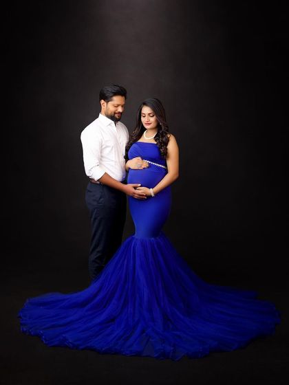 A classic couple's portrait against a dark backdrop. The vibrant blue of her gown provides a beautiful pop of color, creating a simple yet striking image.