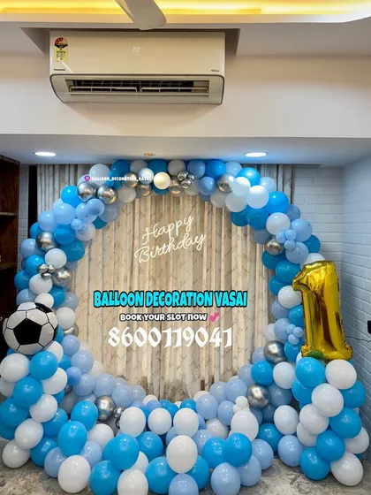 A football theme for a first birthday. The ring backdrop is decorated with blue and white balloons, with a football foil balloon as a central element.