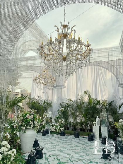 The grandeur of the botanical wedding design, highlighting the scale of the custom wire mesh arches against a backdrop of potted plants and elegant drapery. This image showcases the ability to transform large, open venues.