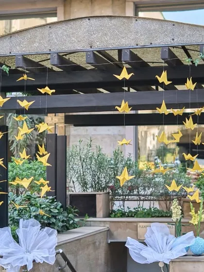For a touch of whimsy, I created a canopy of yellow origami cranes, symbolizing joy and hope, which floated gently over the event space.
