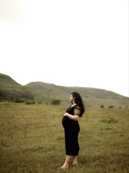 A serene portrait of the mom-to-be standing in a field, looking out at the view. It’s a moment of quiet reflection and anticipation.