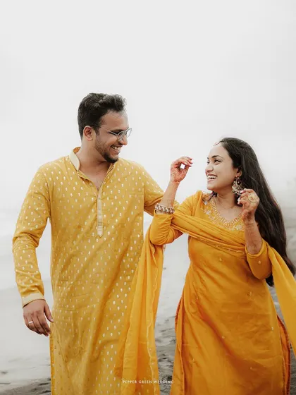 A candid shot of the couple sharing a laugh on the beach, showcasing their easy and natural chemistry.