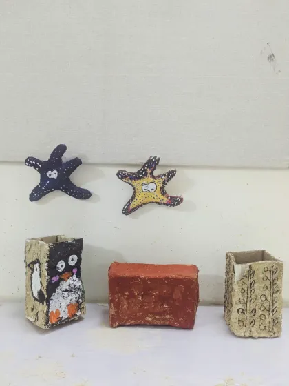 A collection of finished papermache pieces from the Saturday Junior Batch, including pen holders and decorative starfish, all painted and ready to go home.