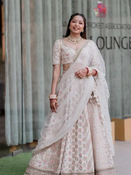 A full-length shot of the client in her beautiful white lehenga, her hair styled in a simple and elegant half-braid.