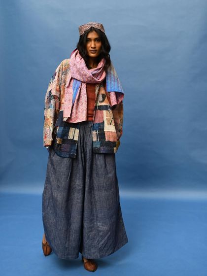 A full-body portrait showcasing a layered look with wide-leg pants and a patchwork jacket. The styling is both comfortable and incredibly chic.