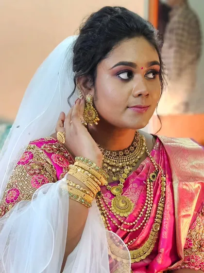A unique Christian wedding look where the bride paired a traditional pink Kanjivaram saree with a white veil. I created a look that beautifully merged both traditions.