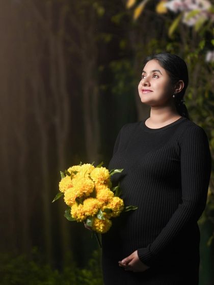 A simple and sweet studio portrait of an expecting mother in a black dress, holding a bouquet of bright yellow marigolds. The pop of color adds a touch of warmth and joy.