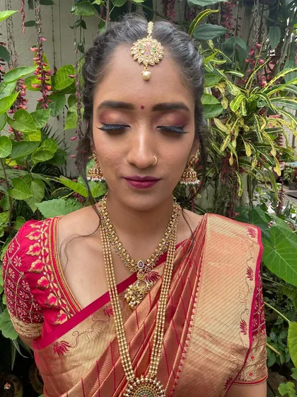 A beautiful outdoor shot of Dr. Rakshitha for her ring ceremony. The makeup features a dramatic smokey eye with a hint of red, paired with a deep berry lip.