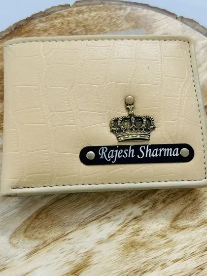 This cream-colored croc-textured wallet is personalized with a name on a black strip and a crown charm, giving it a premium look.