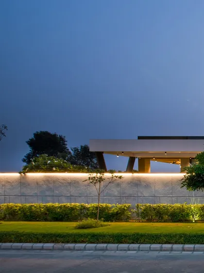 A minimalist shot of the Sonipat residence at night, focusing on the clean line of the illuminated boundary wall against the evening sky.