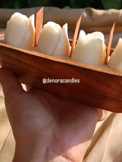 A hand-held view of the white tulip wooden boat candle, showing its size and craftsmanship.