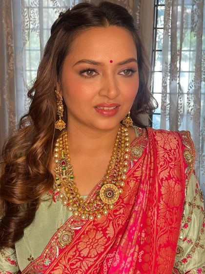 A three-quarter profile showing the soft waves in her hair and the beautiful, glowing finish of the makeup.