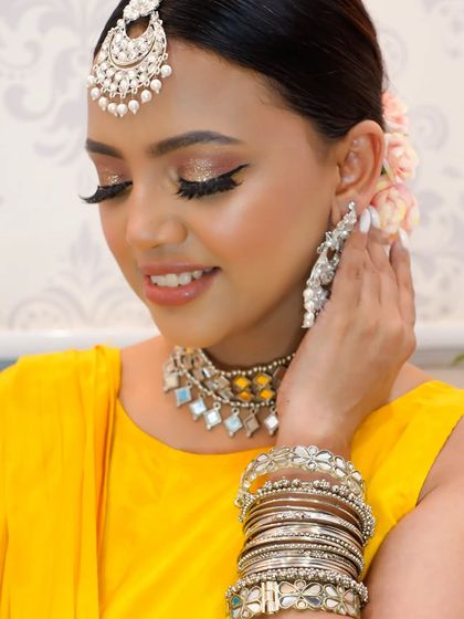 Shine bright with this glittery Haldi makeup look. The focus is on the sparkling pink and yellow eyeshadow, which adds a fun and glamorous touch to the traditional yellow outfit.