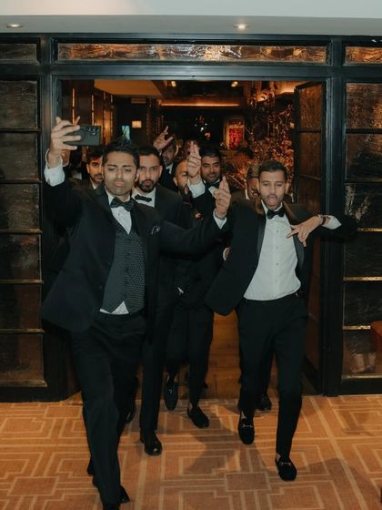 The groom's entourage making a fun and energetic entrance at the reception. This candid shot captures the party atmosphere and the excitement of the groomsmen.