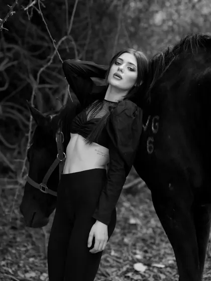 A moody black and white portrait of a model with a horse, perfect for creating a sense of drama and elegance.