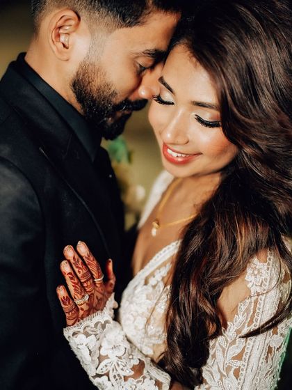A close-up shot focusing on the couple's tender embrace and the intricate details of the bride's henna. This image blends intimacy with cultural details.
