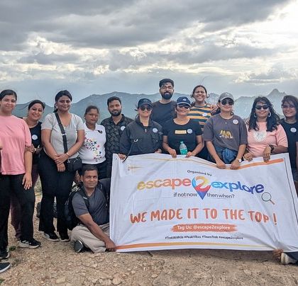 The group proudly holding the banner after reaching the top of a hill near the Adiyogi statue. A sense of accomplishment and togetherness.