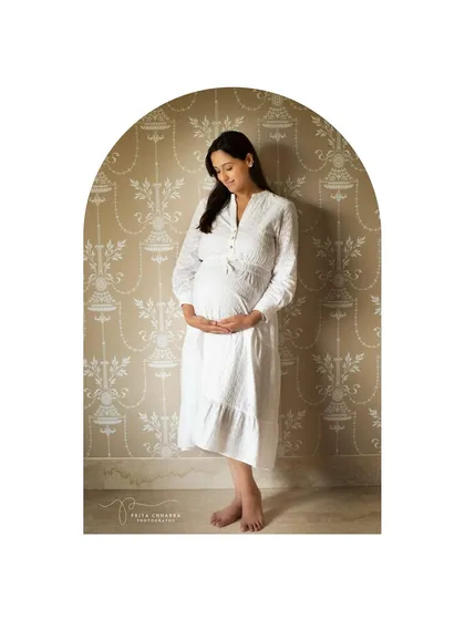 A simple and elegant portrait taken during an at-home session. The arched framing and classic white dress create a timeless look that feels both personal and artistic.