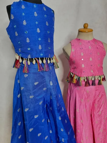 Fun and festive co-ord sets in royal blue and bright pink. These sets feature a crop top with colorful tassels and matching flared pants, perfect for a mehendi or sangeet.