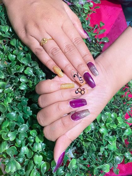 A unique design with purple and gold nails, featuring abstract line art.