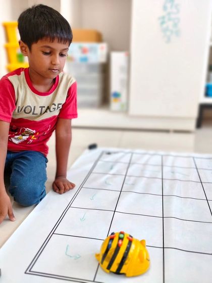 We introduce coding concepts in an age-appropriate way. Here, one of our youngest campers learns sequencing and logic with a screen-free Bee-Bot robot on a grid map.