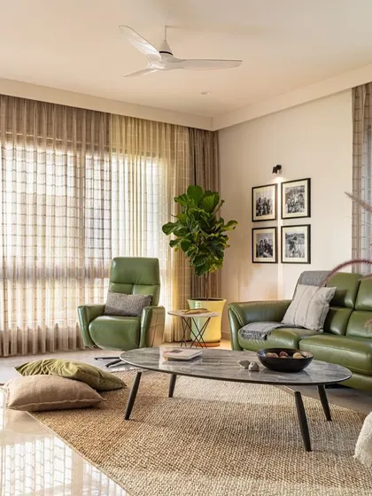 This living room features a mix of comfortable, modern furniture. The green leather sofa and recliner add a pop of color against the neutral backdrop.