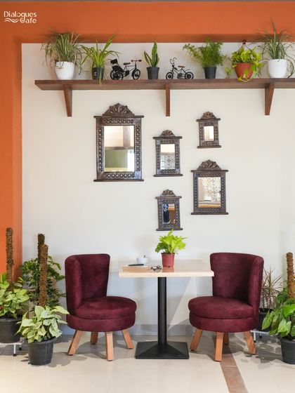 This cozy corner with its plush maroon chairs, antique-style mirrors, and abundant plants is a perfect reflection of my vision: a serene, beautiful space for quality time.